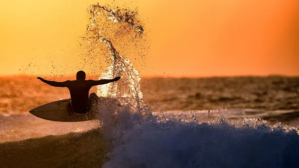 Surfer Rides Sunset Wave by Eyal Bussiba