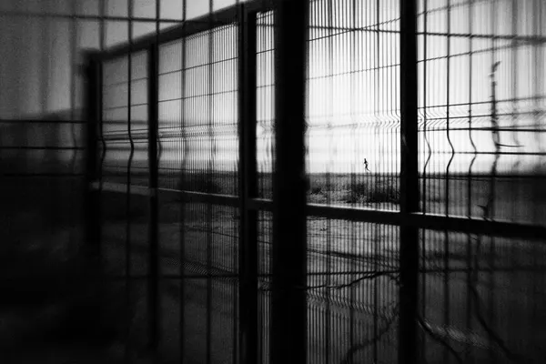 Solitary Figure Beyond Fence by Laura Mexia