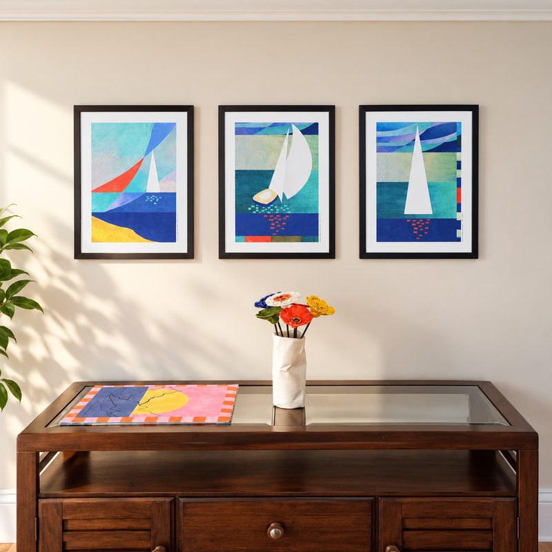 A trio of framed sailboat prints above a wooden sideboard